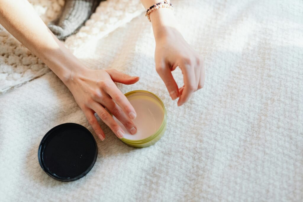 Close-up of hands applying cream on a soft, textured surface, emphasizing relaxation and skincare routine.