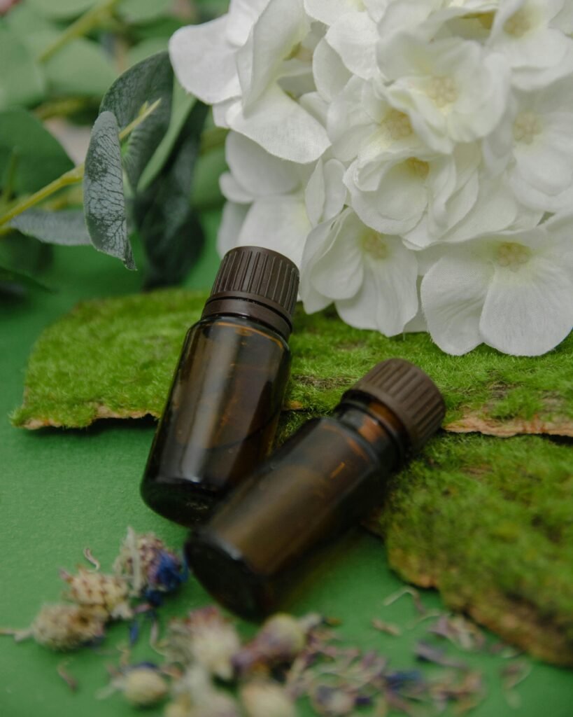 Essential oil bottles placed on moss with white flowers, creating a natural and calming scene.